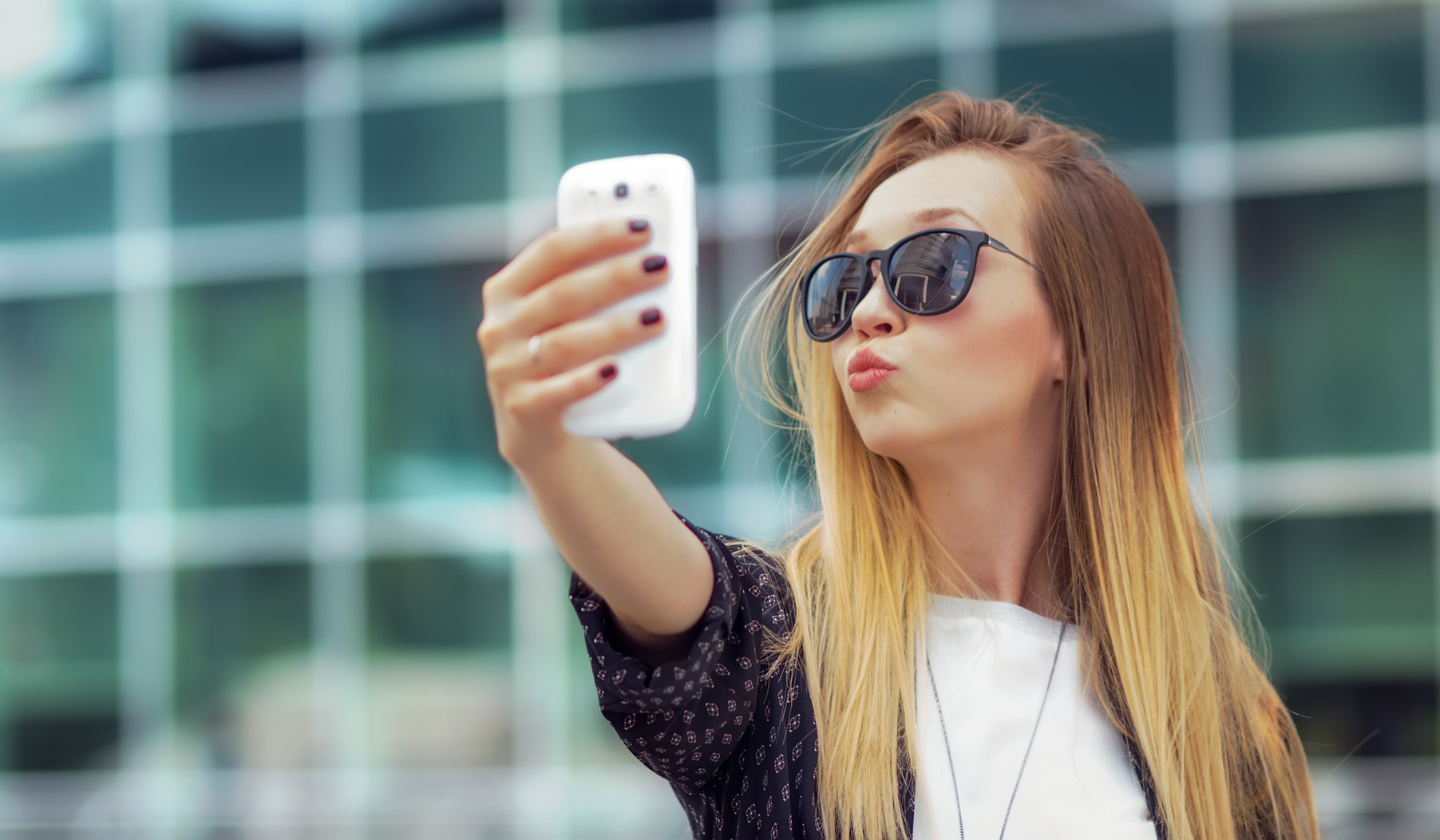 Young happy girl make a selfie with his smartphone, outdoors