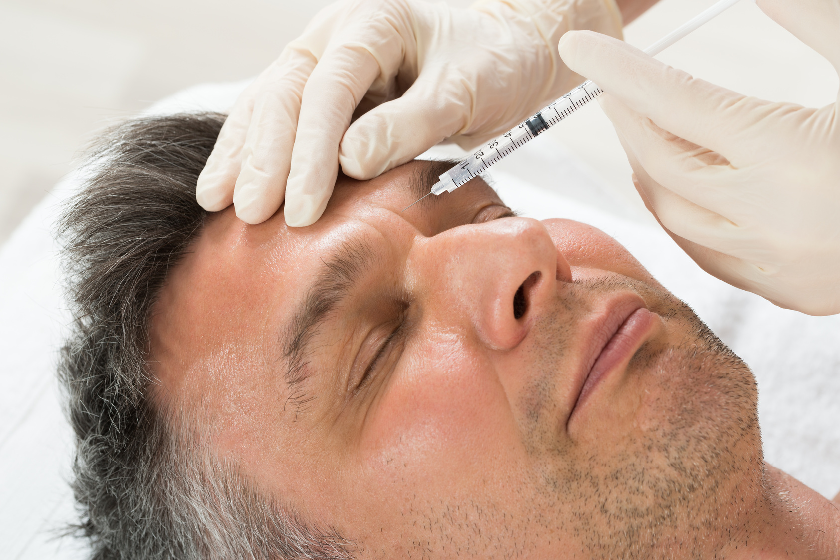 Mature Man Receiving Cosmetic Injection With Syringe In Clinic